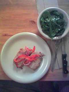 a plate of pork with a bowl of salad on the side