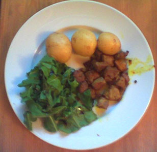 a plate of pork, potatoes and salad
