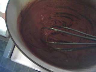 a pot with deep brown roux being mixed with a whisk