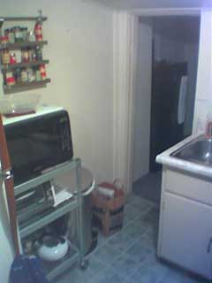 a cart with a microwave on it, near the fridge and the sink