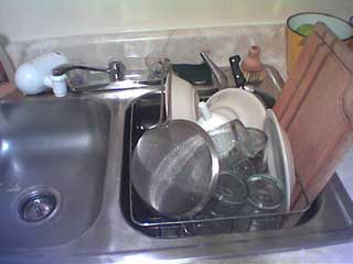 a metal sink with a full dish-draining rack in it