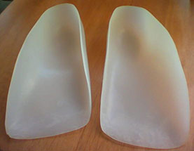 two orthotics next to each other, white plastic
