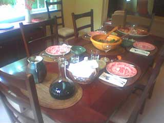 a dinner table, with full china settings for four, a wine decanter and a salad